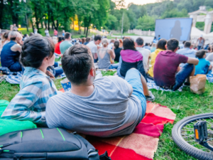 This is an image of a group of people on a lawn watching an outdoor movie.
