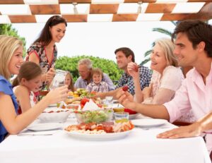 This is an image of an extended family eating outside on a back porch or patio.