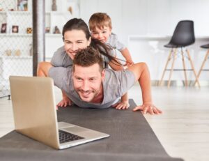 This is image of a dad, mom and son laying on the floor with a laptop open in front of them. 