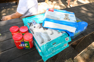 4 pack of Jif peanut butter, dog food and puppy training pads sitting on a picnic table.