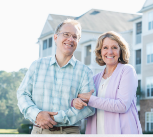 This is an image of an older couple standing in front of a condo or apartment complex.