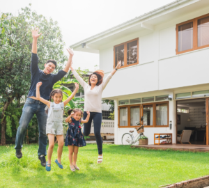 This is an image of a happy family jumping in the air in front of a house.