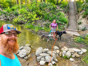 Kimberly Murphree and her husband with their dogs at the creek at Camp Ben McCulloch near Austin