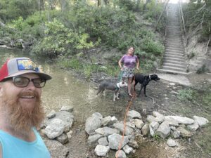 Kimberly Murphree and her husband with their dogs at the creek at Camp Ben McCulloch near Austin