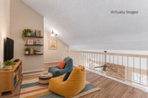 Virtually staged upstairs loft with seating, a sloped ceiling, and railing overlooking the living room at 2100 Kippling Drive.