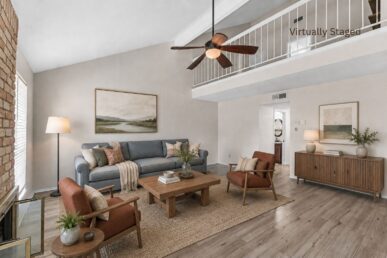 Virtually staged living room with vaulted ceiling, brick fireplace, ceiling fan, and open loft above at 2100 Kippling Drive.