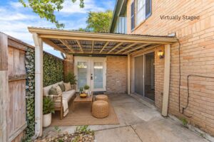 Virtually staged covered patio with brick walls, French doors, sliding glass doors, and a privacy fence at 2100 Kippling Drive.